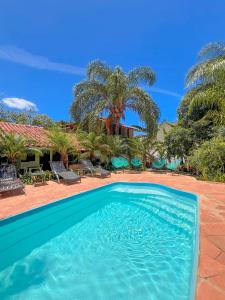 a swimming pool in front of a house with palm trees at Pousada Adega Cipo in Serra do Cipo