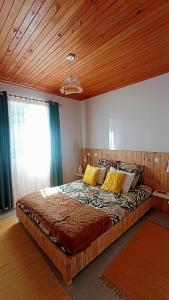 - une chambre avec un grand lit et un plafond en bois dans l'établissement Kanela Guest house, à Machico