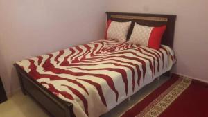 uma cama com lençóis e almofadas de listras vermelhas e brancas em Ketama كتامة em Ketama