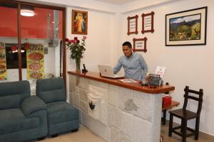 a man sitting at a counter with a laptop at Inti Pacha Palace Machupicchu in Machu Picchu