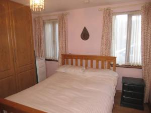 a bedroom with a bed with white sheets and windows at Borodino Studio Apartment in Enniscorthy