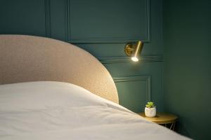 - une chambre avec un lit blanc et une porte verte dans l'établissement La Belle Échappée, à Montgeron