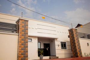 a white house with a brick pillar at Bae apartment in Oba Ile