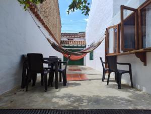 een tafel en stoelen op een veranda met een hangmat bij ALMANIK VIAJERO in Villa de Leyva