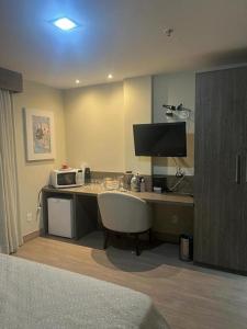 um quarto de hotel com uma secretária e um micro-ondas em Alugo 1 Suite 210 no Mont Blanc em Nova Iguaçu