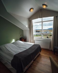 a bedroom with a large bed and a large window at Sel - Hótel Mývatn in Myvatn