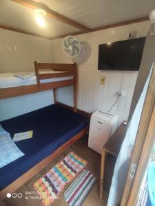a small room with a bunk bed and a television at Pousada Morada das Flores in Ilha do Mel