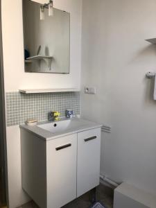 ein weißes Badezimmer mit einem Waschbecken und einem Spiegel in der Unterkunft Location cure ou vacances dans maison charentaise centre ville in Saujon