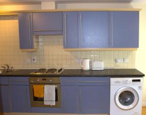 a kitchen with blue cabinets and a washing machine at Spacious 2BR flat in Central London near Elephant and Castle station in London