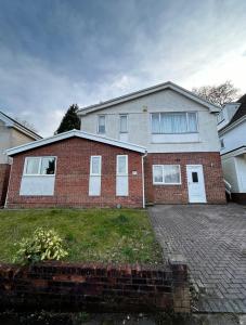 uma casa de tijolos com portas brancas e uma entrada de tijolos em 35 Southerndown Avenue em Swansea