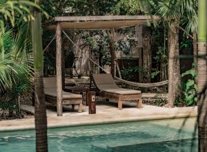 a gazebo with a chair next to a swimming pool at Aldea Xaan Ha Tulum in Tulum