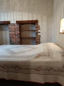Bett in einem Zimmer mit einem gemauerten Kamin in der Unterkunft La petite maison en Puisaye in Dampierre-sous-Bouhy