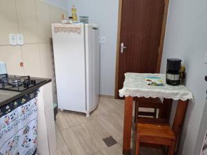a kitchen with a white refrigerator and a table at Edícula c/ wifi e banheiro externo em Capão Bonito in Capão Bonito