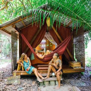 a group of people sitting in a hammock in a house at Canto de Jurema Corumbau Glamping, Chalé, Acolhimento e Sustentabilidade in Corumbau