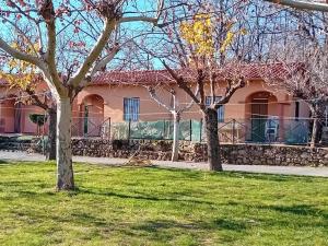 a pink house with trees in the grass at CAMPING-BUNGALOWS-CABAÑAS LA VERA in Jarandilla de la Vera