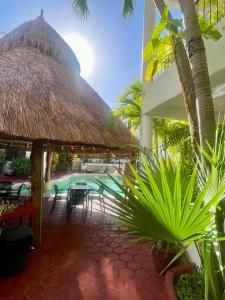eine Terrasse mit einem Strohschirm und Stühlen sowie einem Pool in der Unterkunft Marisol Beach in Playa del Carmen