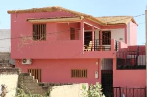 a pink house with a balcony at Ker Vento in Rufisque