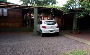 a white car is parked under a garage at Hostería Montes in San Ignacio