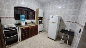 una pequeña cocina con nevera y fregadero en Casa piscina 8 pessoas en Saquarema