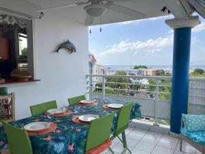 a dining room with a table and chairs and a balcony at Madi Sun - Spacieux - Plage 250m in Les Trois-Îlets