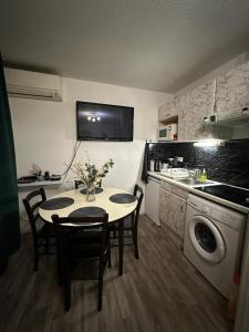 uma cozinha com uma mesa e cadeiras e um lavatório em Ararat em Lourdes