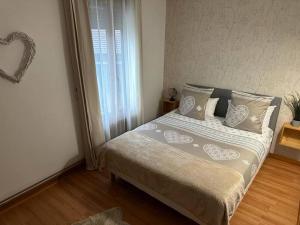 sypialnia z łóżkiem z poduszkami i oknem w obiekcie La Maison Richard w mieście Thizy-les-Bourgs