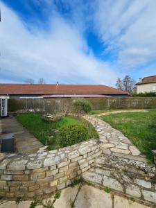 einen Steinweg in einem Hof mit einer Steinmauer in der Unterkunft La Maison Richard in Thizy-les-Bourgs