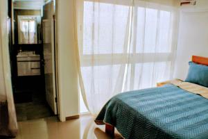 1 dormitorio con cama y ventana grande en Flamingo Plateau 1A apt on Rua Pedonal Praia Cape Verde en Praia