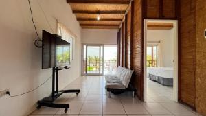 Hospedaje & Casa Playa AURORA في زوريتوس: غرفة معيشة فيها تلفزيون وسرير