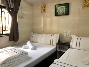 2 camas en una habitación de hotel con sábanas blancas en Sun Guest House en Hong Kong