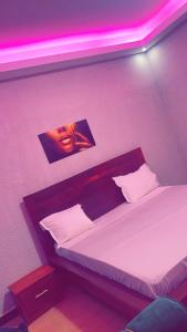 a bedroom with a bed with a purple lighting at Hôtel Résidence Aïcha Tambacounda in Tambacounda