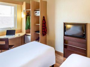 um quarto com uma cama, uma secretária e uma televisão em ibis Blumenau em Blumenau