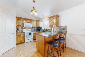 una cocina con armarios de madera y una isla con taburetes. en The Swisher House, en Pocatello