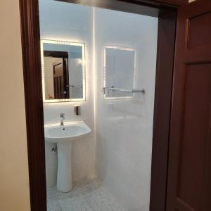 a white bathroom with a sink and a mirror at Khair Jewaar Apartments Al Madinah in Al Madinah