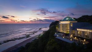 Umana Bali, LXR Hotels & Resorts في أُلُواتو: مبنى على منحدر بجوار المحيط