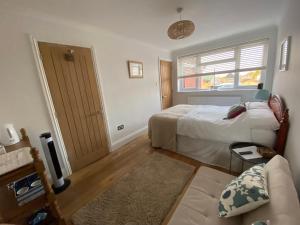 a bedroom with a bed and a window and a couch at Bright Suite in Whitstable