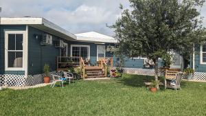 a blue house with a yard with chairs and a tree at Quiet Condo close to Laguna Madre -B in Corpus Christi