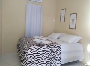 Bett in einem Zimmer mit einer Zebradecke in der Unterkunft Pousada Praia Dos Coqueiros in Conde