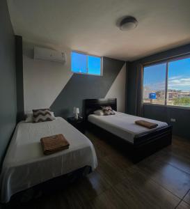 um quarto com 2 camas e uma grande janela em Departamento Raya em Puerto Ayora