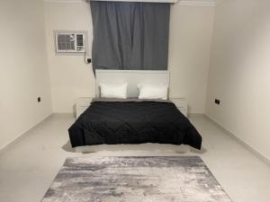 a bedroom with a bed with a black comforter and a window at Almansour Laxury Apartement in Al Madinah