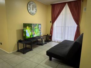 a living room with a television and a clock on the wall at Departamento céntrico con estacionamiento in Concepción