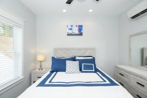 een witte slaapkamer met een bed met blauwe kussens bij BayRidge house by Quiet Waters, Thomas Point Parks in Annapolis
