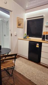 a kitchen with a black dishwasher and a flat screen tv at Tiny Retreat Noosa in Cooroibah