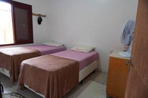 Zimmer mit 2 Betten, einem Ventilator und einem Fenster in der Unterkunft Casa aconchegante in Passo de Torres