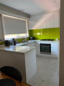 a kitchen with white cabinets and a green wall at Balcombe Retreat in Mount Martha