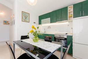 a kitchen with green cabinets and a table with a vase of flowers at Apartments by the sea Cove Gornja Krusica, Solta - 20021 in Stomorska