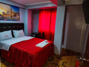 1 dormitorio con 1 cama con manta roja y cortina roja en Hostal Paris, en Lima