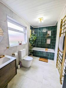 a bathroom with a toilet and a sink and a tub at Beautiful 2 BR home close to the city in Morpeth