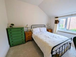 a bedroom with a bed and a green dresser and a window at Beautiful 2 BR home close to the city in Morpeth