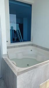 a white bath tub with a window in a bathroom at Grand Diamond Beach Tonsupa in Tonsupa